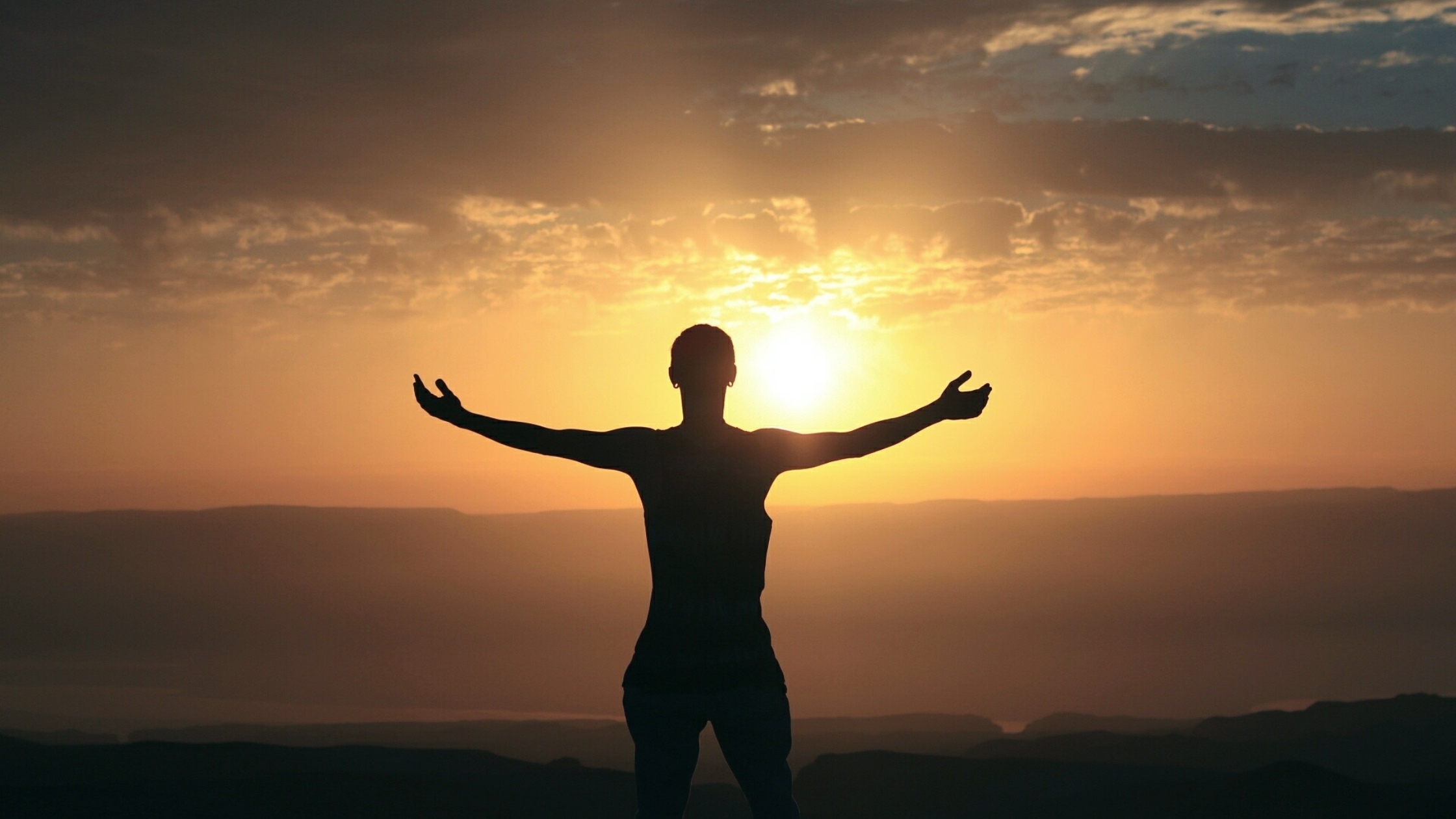 Spiritual Awakening Journey - A silhouette of a person embracing the sunrise, symbolizing spiritual awakening and presence.